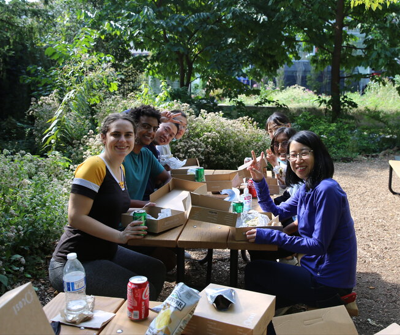 Members of the Jin Lab gather at a picnic table at a park